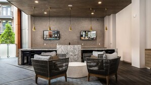 A modern kitchen with a marble island, two wicker chairs, pendant lights, and a large window overlooking a cityscape. - Landing | Incredible 1BD, Courtyard, Gym (Fort Worth)