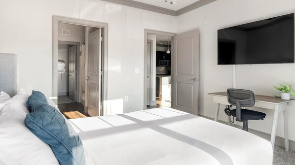 Une chambre d’hôtel moderne équipée d’un lit, d’un bureau, d’une chaise, d’une télévision et d’un placard.