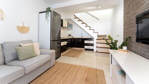 Une cuisine moderne dotée d’un réfrigérateur encastré, un coin repas avec un canapé et un escalier menant à un niveau supérieur.