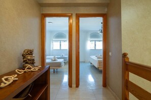 A hallway leading to a bedroom with a bed, a nightstand, and a wooden bench.