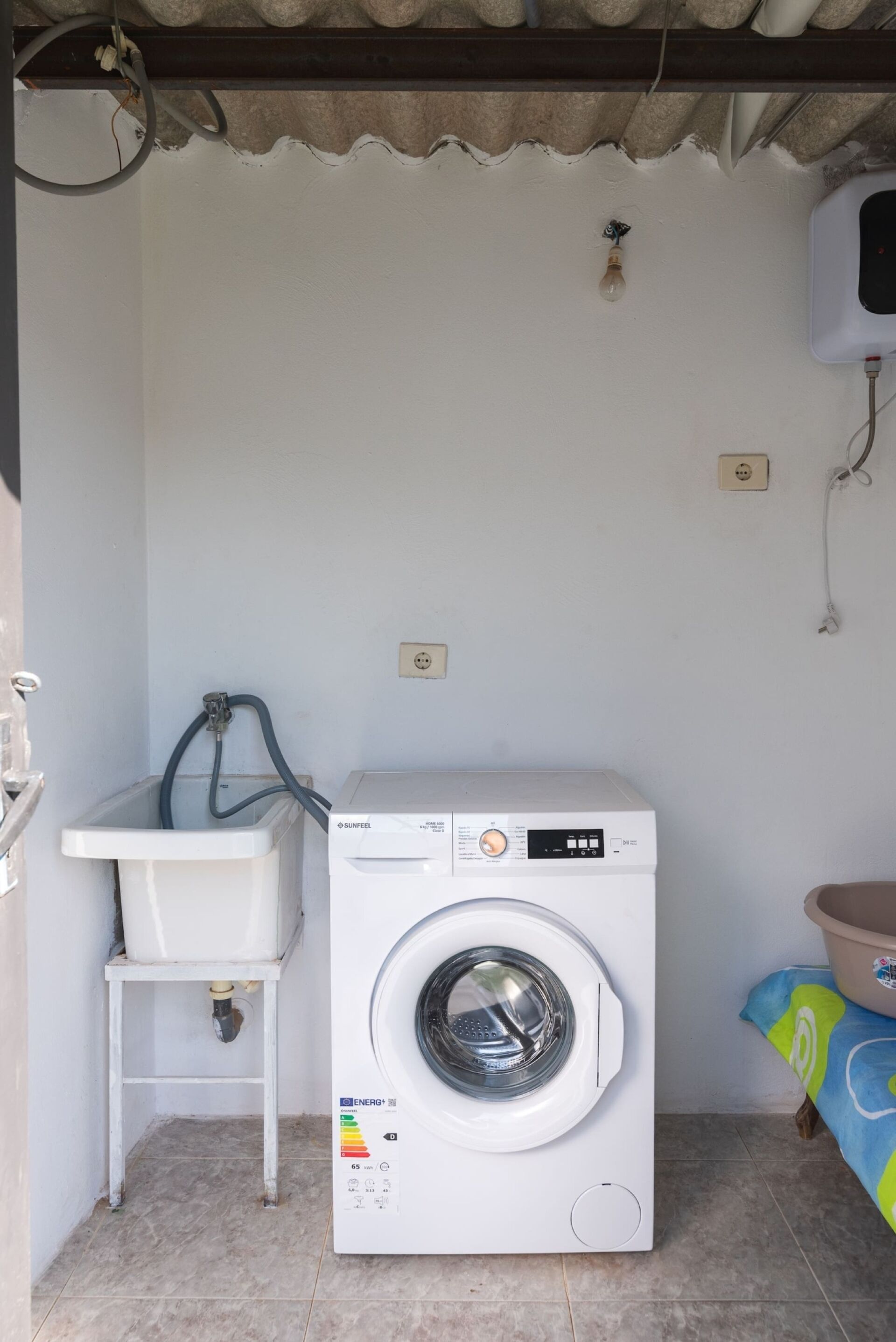 A compact laundry area with a washing machine, a sink, and a hose.
