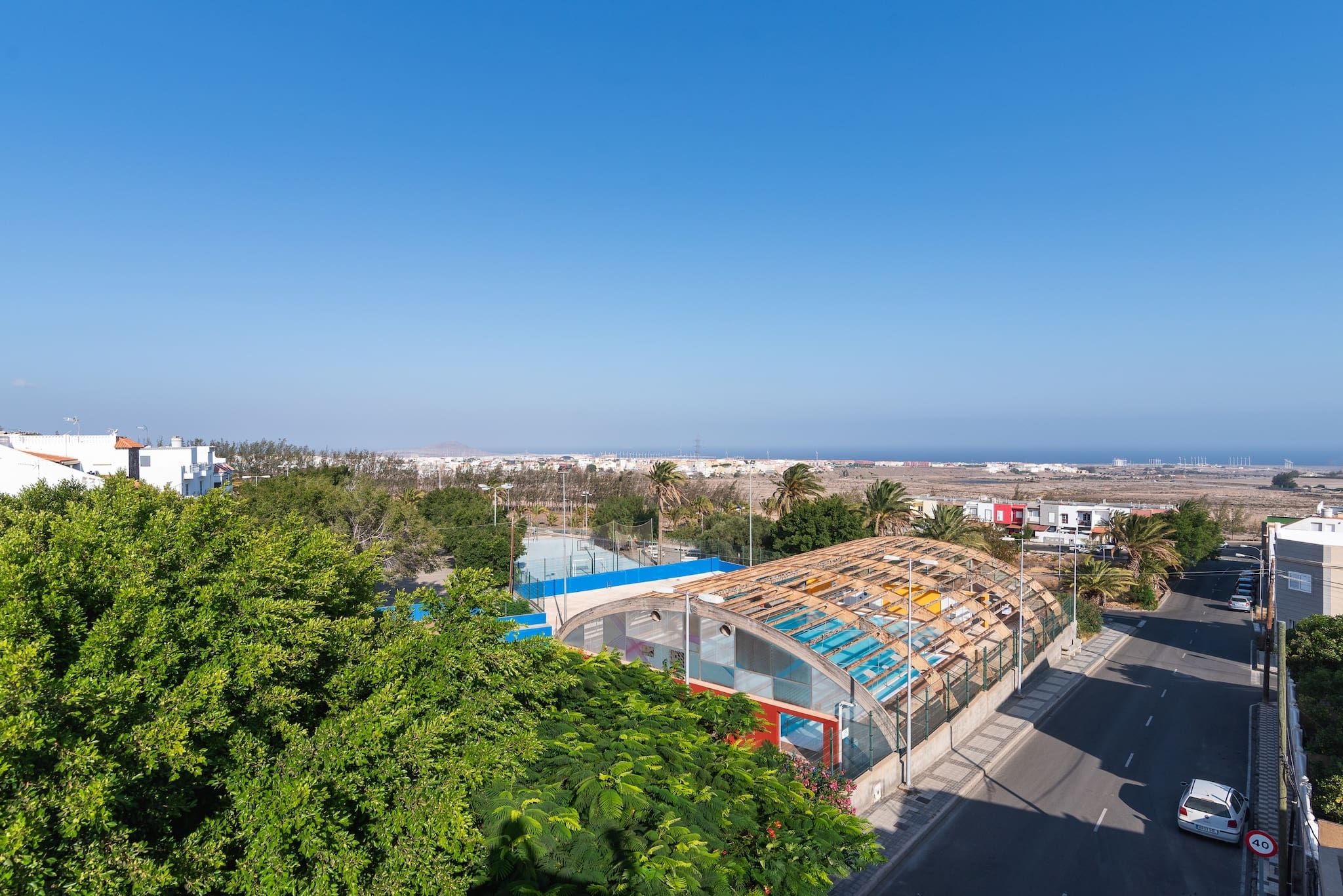 Une vue sur la côte, avec une piscine, un bâtiment aux lignes courbes et une route signalée par un panneau indiquant la limite de vitesse.