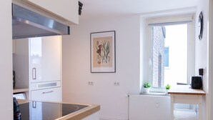 A modern kitchen with a built-in stove, white cabinetry, and a window with a view of the outside.