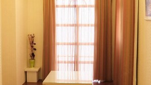 Una habitación con ventana, una mesita y una planta en maceta.