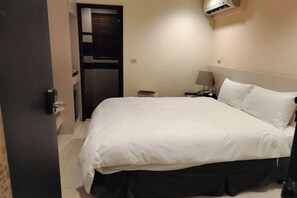 A hotel room with a bed, bedside table, lamp, and an air conditioning unit. - F Hotel Sanyi (Miaoli)