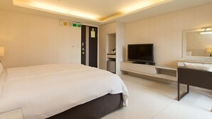 Una habitación de hotel con una cama, televisor, escritorio y espejo.