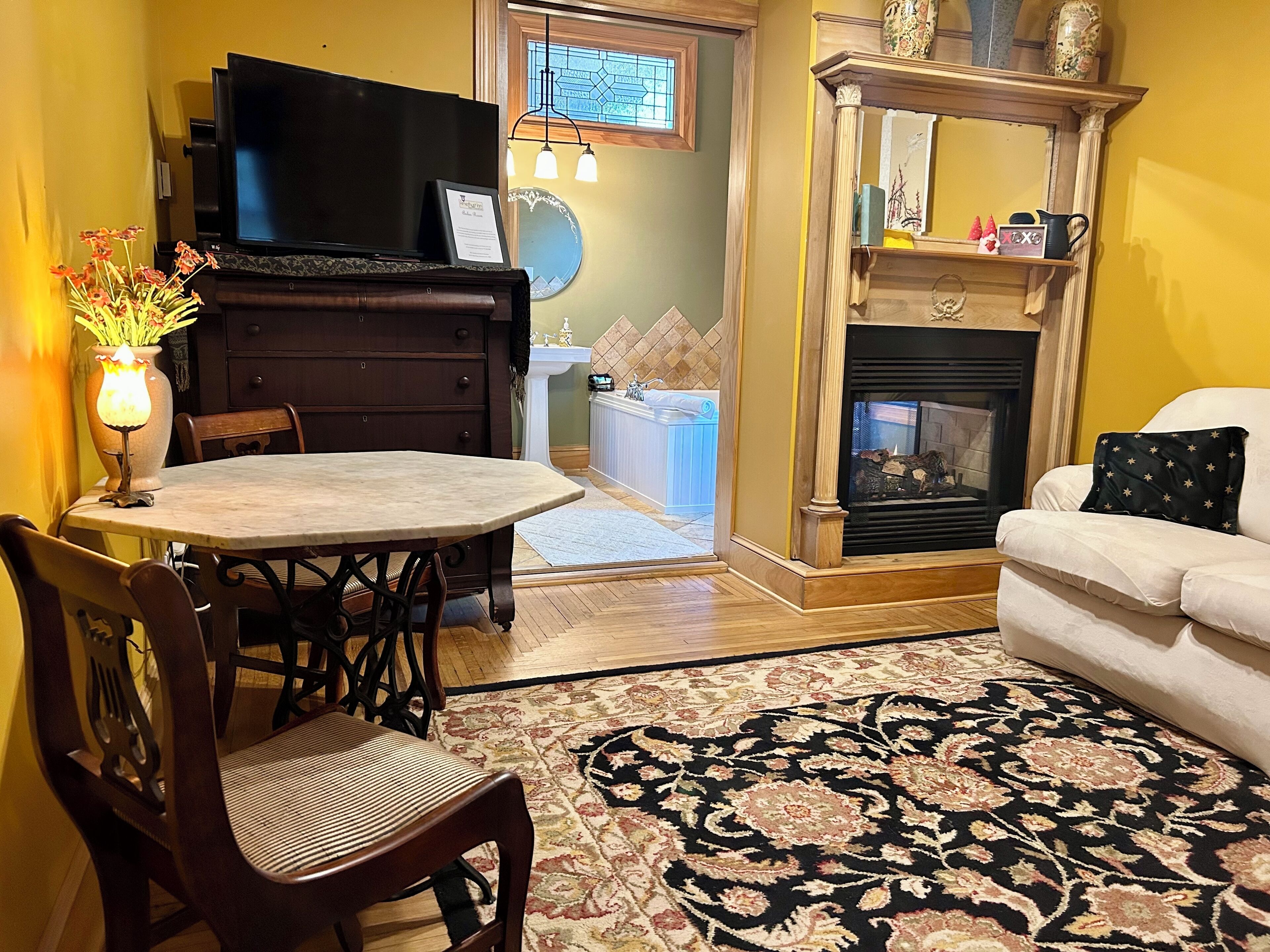 Un salon avec une cheminée, un téléviseur, un coin repas avec des chaises et un canapé.