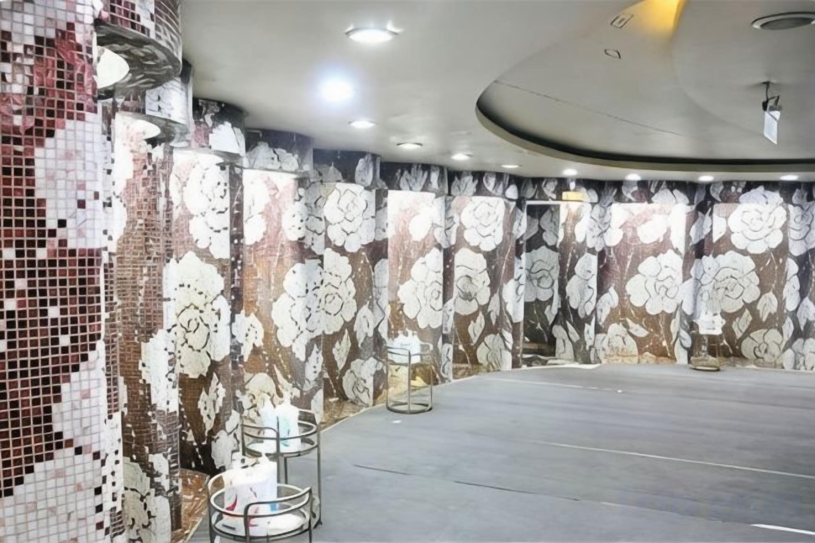 Une pièce dotée d’une grande table ronde, d’un mur orné de motifs et d’un plafond pourvu d’un éclairage encastré.