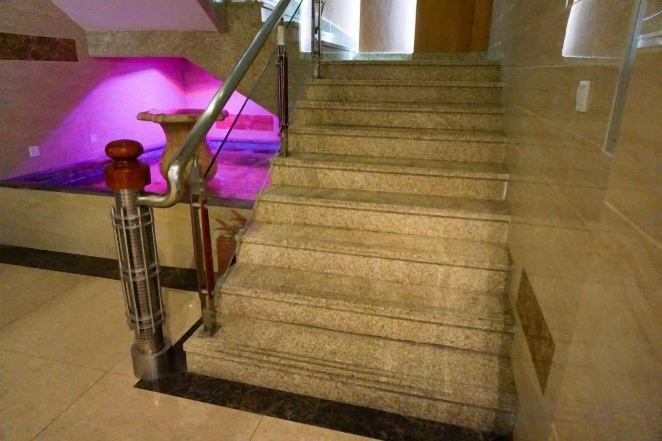 A carpeted staircase with a handrail and a wall-mounted light fixture.