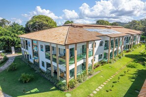 A modern multi-story building with a tiled roof, large windows, and a well-maintained lawn. - Ilhéus North Residence (Uruçuca)
