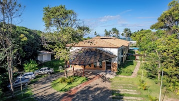 Una propiedad residencial con un patio cubierto, una piscina y un coche estacionado en la entrada.