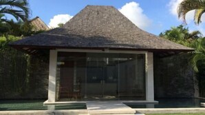 Un bâtiment moderne doté d’un toit en pente, de grandes fenêtres en verre et d’un espace d’entrée pavé.