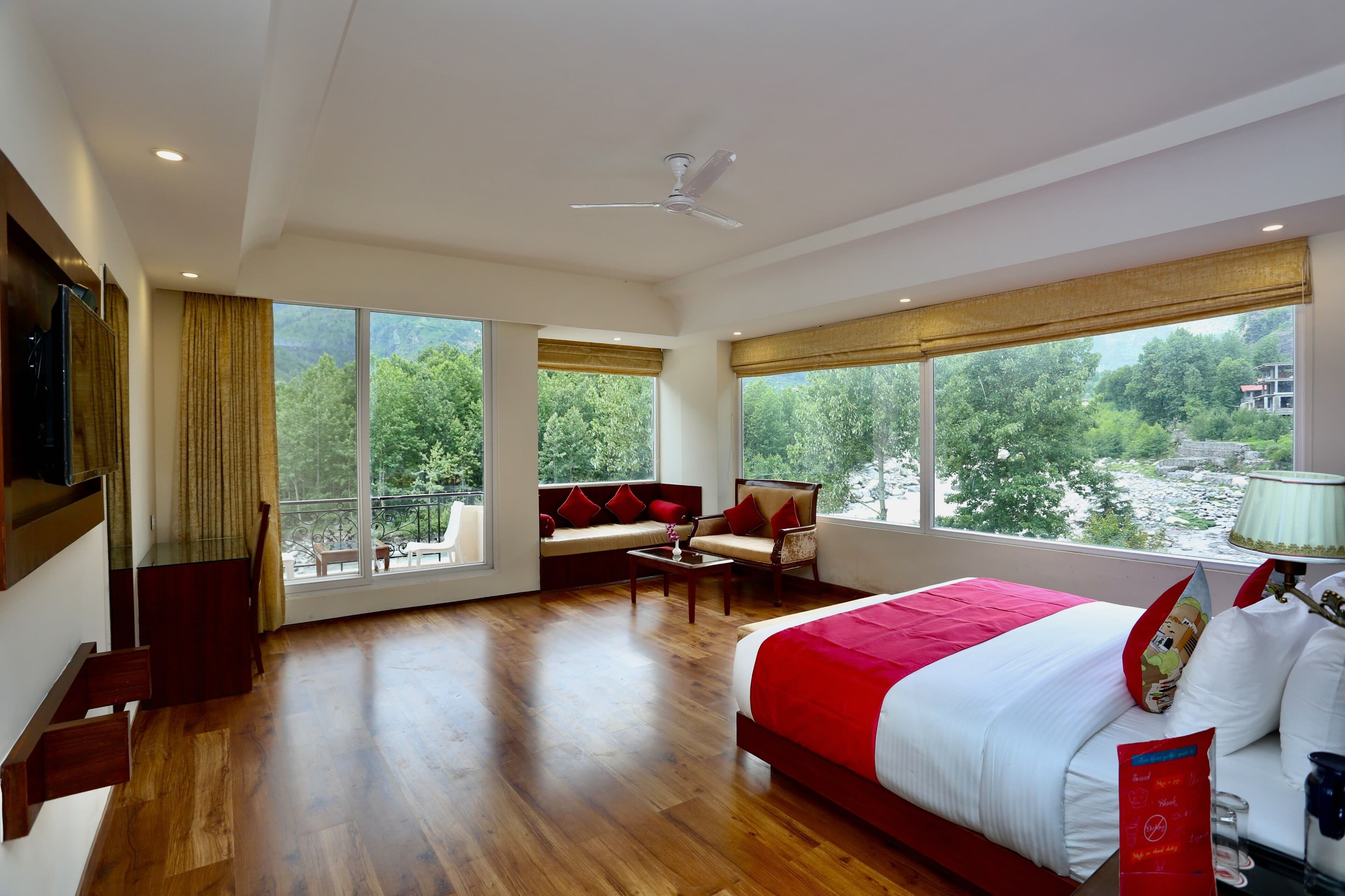 Un dormitorio amplio con una cama grande, un sofá y una mesita de centro. Varias ventanas ofrecen vistas al exterior.