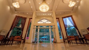 A spacious lobby with chandeliers, large windows, and seating areas. - The Allure Grand Resort  (Manali)