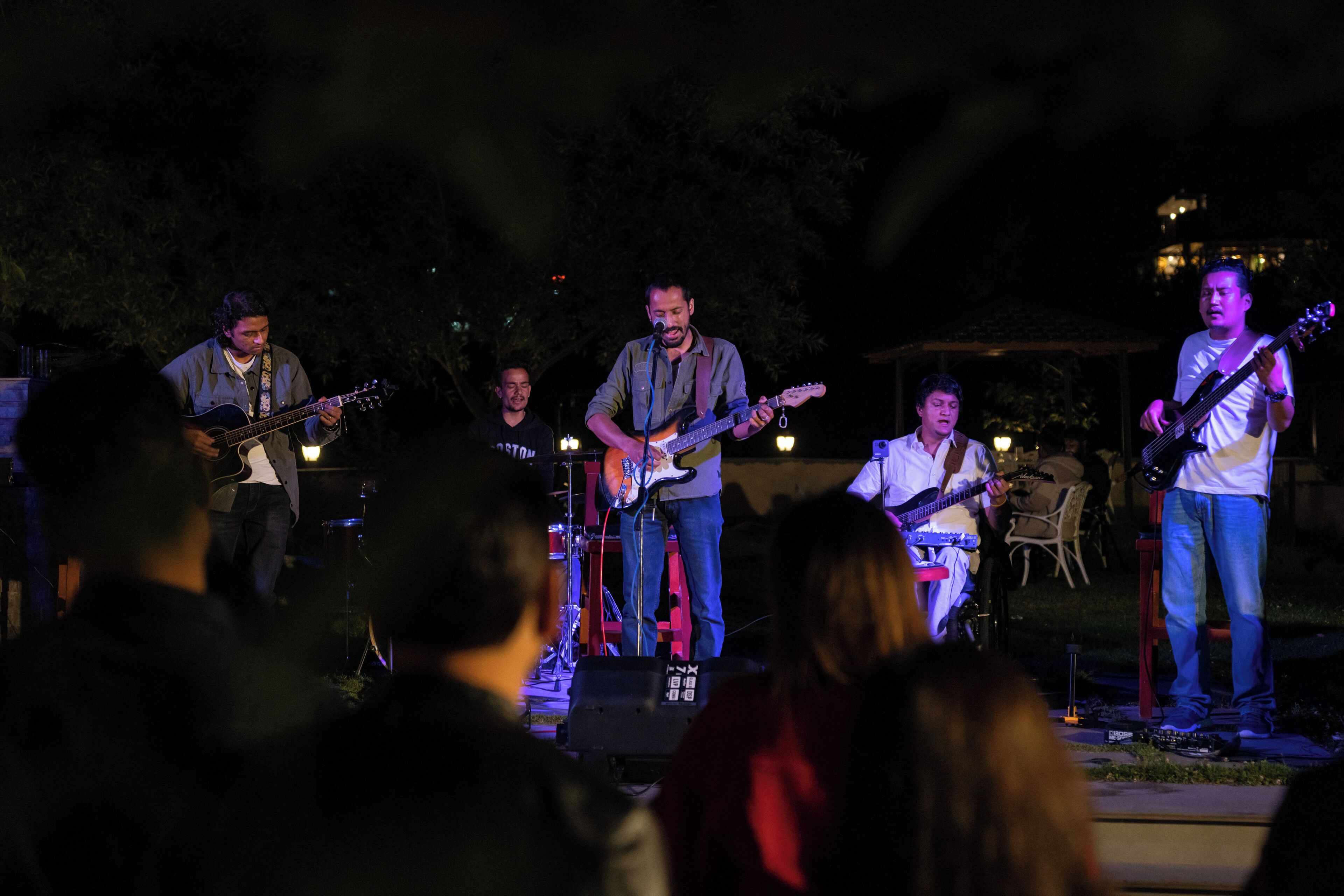 Una banda tocando en un escenario al aire libre, con gente en primer plano.