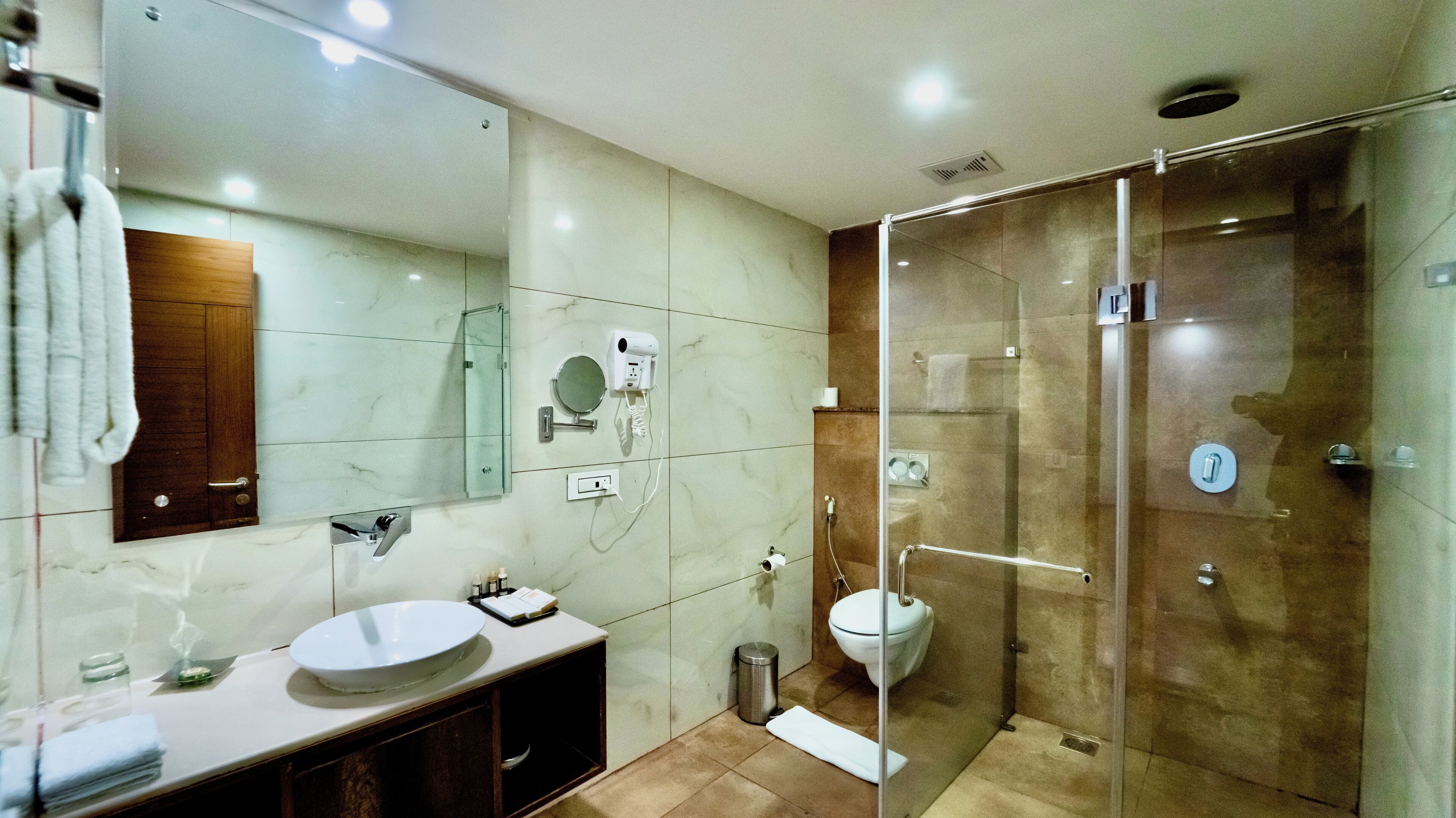 Een moderne badkamer met een glazen douchecabine, een grote spiegel en een witte wasbak.