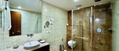 A modern bathroom with a glass-enclosed shower, a large mirror, and a white sink.