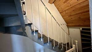 Uma escada com guarda-corpos brancos e teto de madeira.