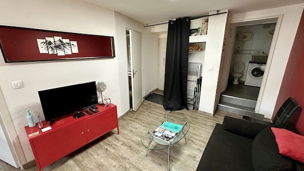 Cozy living space with a flat-screen TV, glass coffee table, and comfortable sofa.