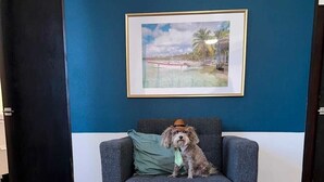 A room with a grey sofa against a blue wall, a framed picture above it, and a wooden coffee table with plants in front. - Newly renovated 2-bed, 2-full bath condo with large pool, minutes from the beach (Carolina)