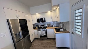 A modern kitchen with white cabinets, stainless steel appliances, and a wooden countertop. - Newly renovated 2-bed, 2-full bath condo with large pool, minutes from the beach (Carolina)