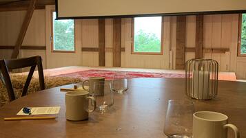 Un salón de conferencias con una pantalla grande que muestra 'Øvre Sem Gard', una mesa de madera con sillas y varios objetos como tazas y vasos.