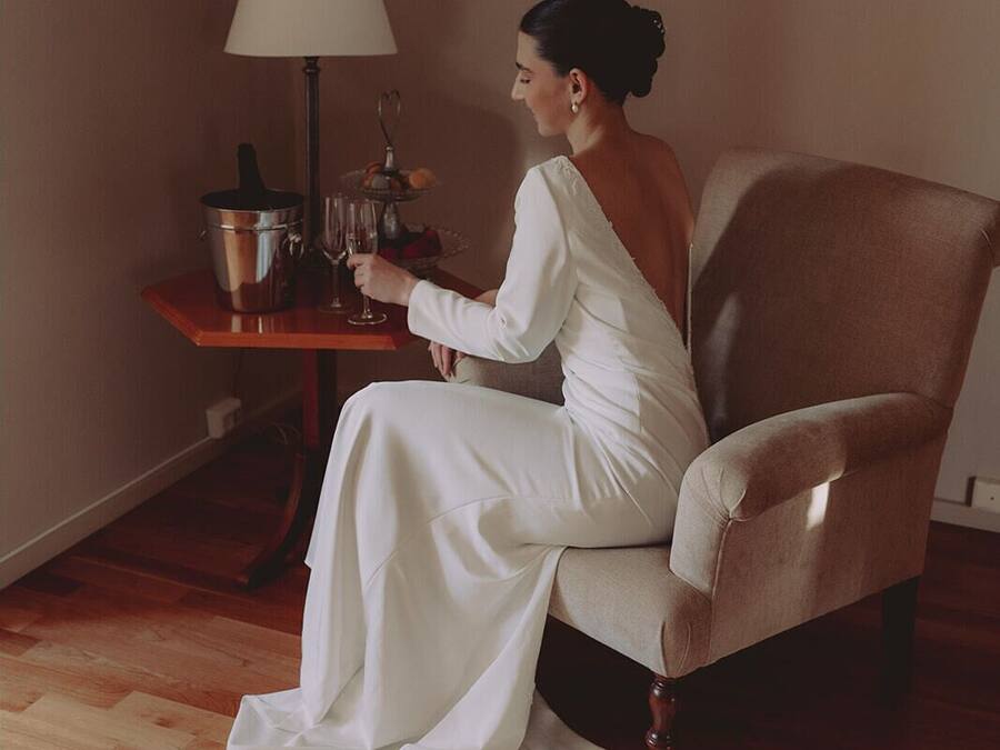 Une pièce avec un plancher en bois, une chaise, une table avec une lampe et un diplôme encadré accroché au mur.