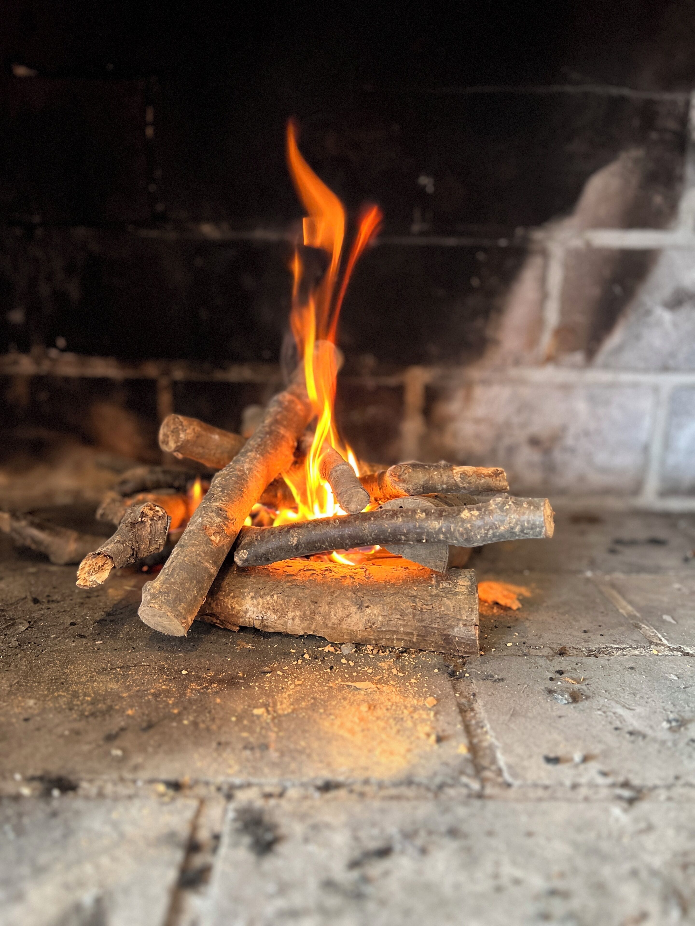 Primer plano de un fuego ardiendo con leña en una chimenea.