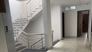 Un intérieur moderne avec un escalier, un banc en bois et un couloir menant à une porte.
