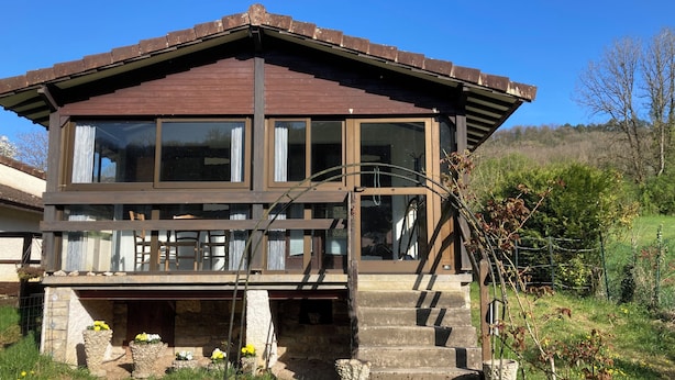 A two-story house with a stone foundation, large windows, and a wooden deck. - Chalet at the end of the world.    (Cormot-Vauchignon)