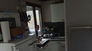 A compact kitchen with a refrigerator, microwave, and a window with a view of greenery. - Chalet at the end of the world.    (Cormot-Vauchignon)