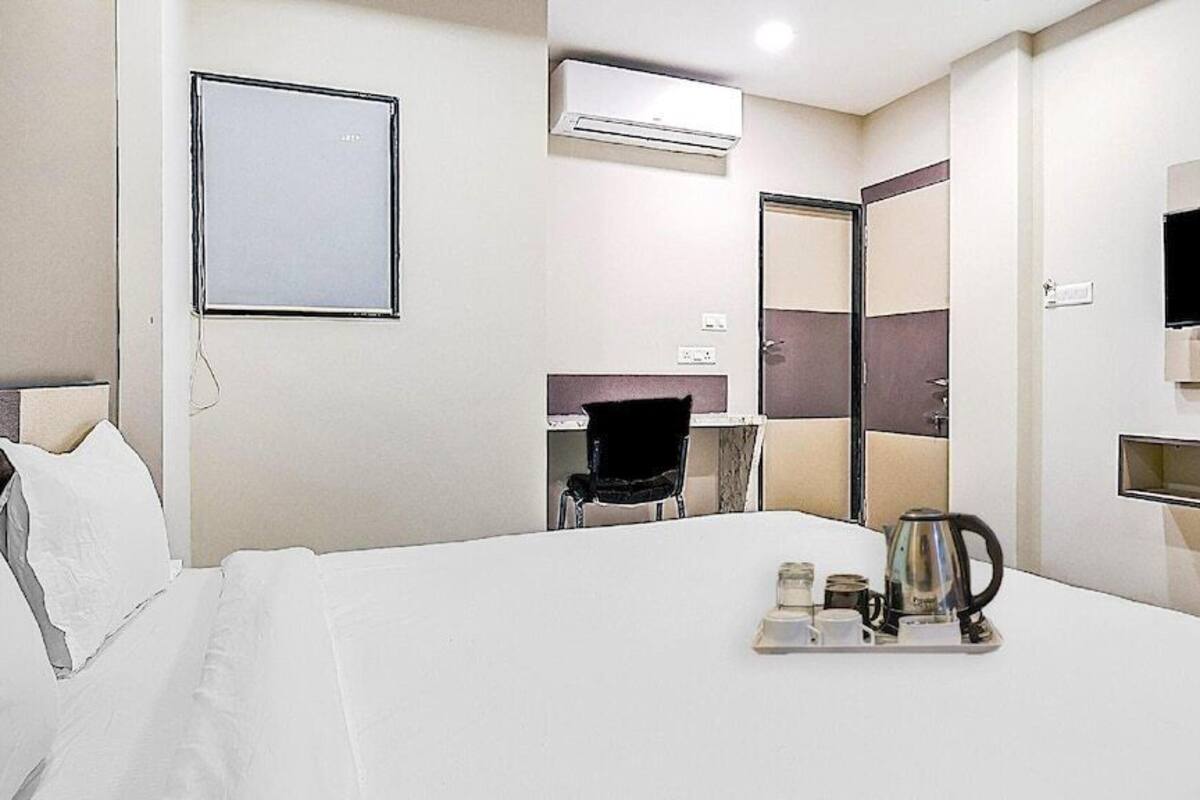 Ein Hotelzimmer mit einem Bett, einem Nachttisch mit einer Auflage, einem Sessel, einem Fernseher und einer Klimaanlage.