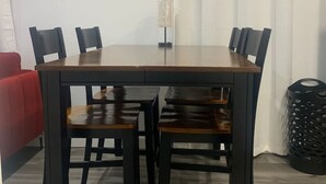 Ein Essbereich mit einem rechteckigen Tisch, sechs Stühlen, einem roten Sofa, einem gerahmten Kunstwerk und einer Lampe.