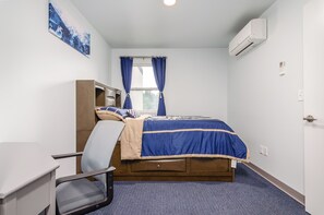 Ein Schlafzimmer mit Bett, Schreibtisch und Klimaanlage.