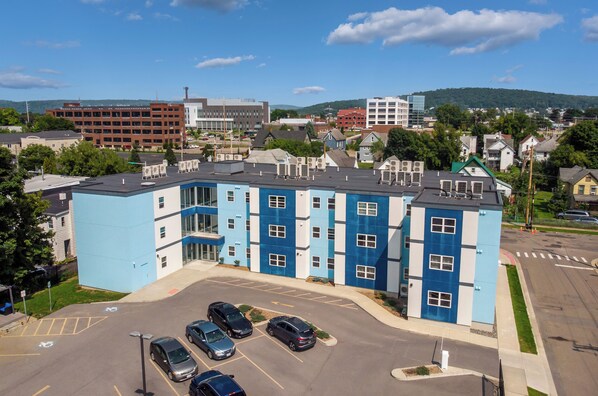Ein mehrstöckiges Gebäude mit blau-weißer Fassade, Parkplatz und einer umliegenden Stadtlandschaft.