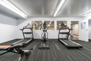Ein Fitnessraum mit Laufbändern, Fahrrädern und einem Rudergerät.