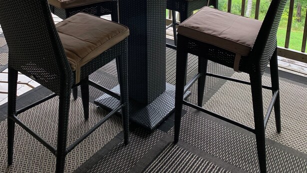 Un espacio de estar al aire libre cubierto con una mesa y sillas, con vista a un cuerpo de agua y vegetación.