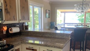 Una cocina con armarios de madera, encimera de granito, estufa de acero inoxidable y un perro de pie en el centro.