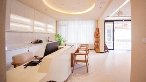 Une cuisine moderne dotée d’un îlot central, d’un coin repas avec des chaises en bois et d’une grande fenêtre ornée de rideaux légers.
