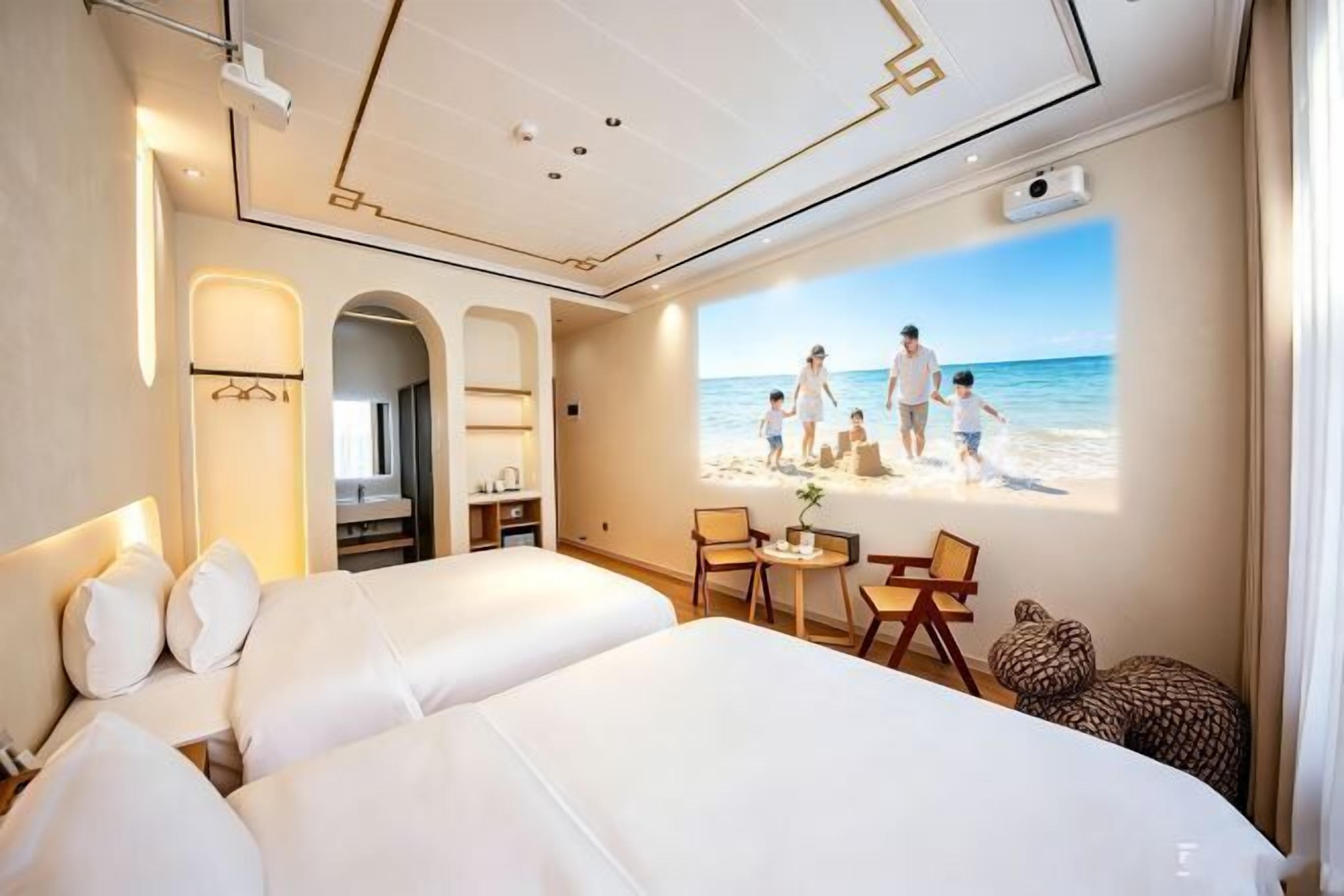 Une chambre d’hôtel avec deux lits, un bureau et une grande fenêtre donnant sur la plage.