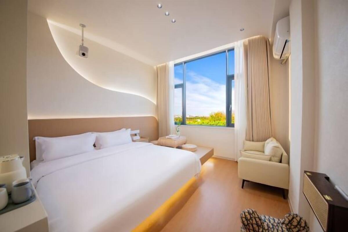 Une chambre d’hôtel moderne dotée d’un grand lit, d’un canapé, d’une fenêtre avec vue et d’un système de climatisation.