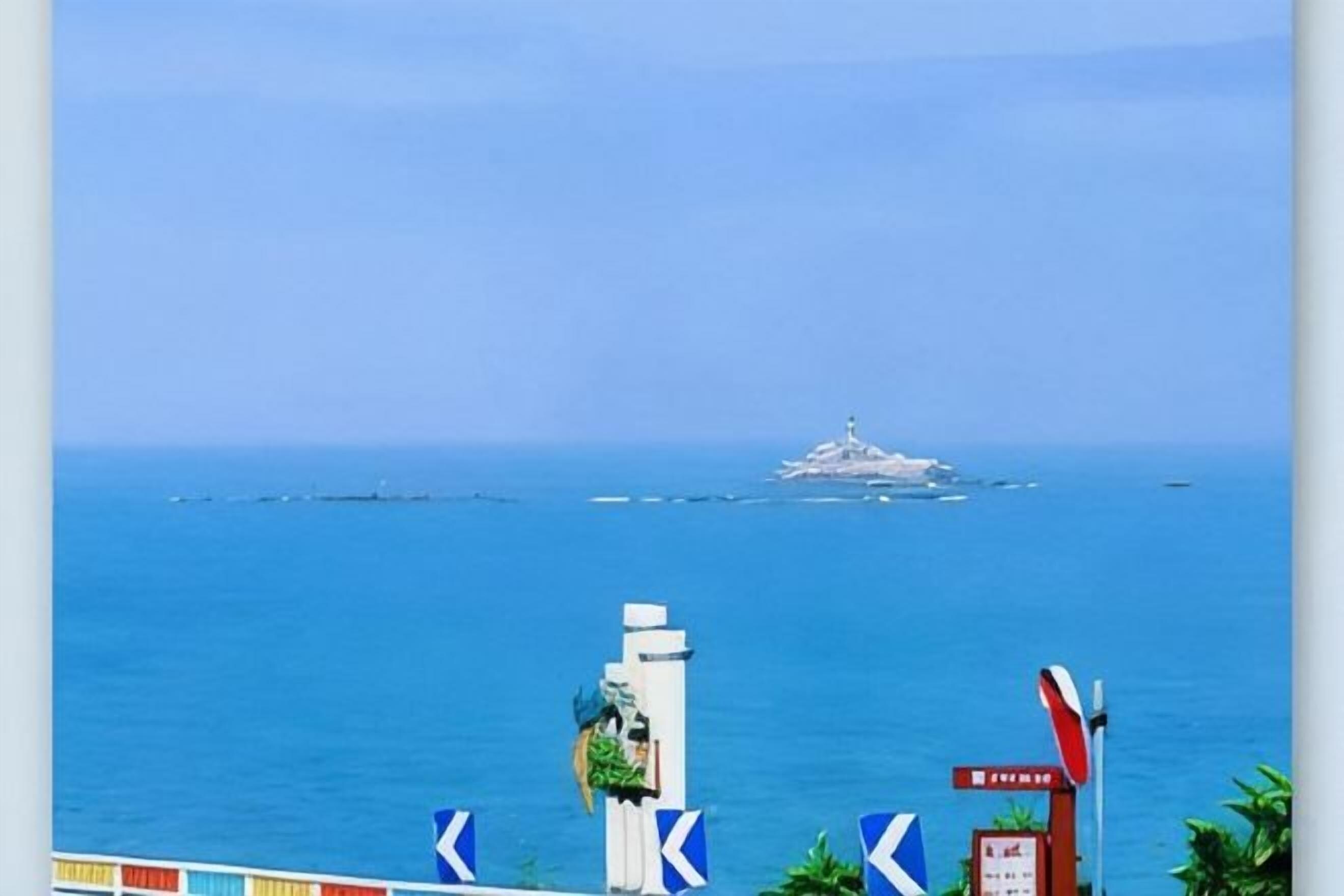 A coastal view with a clear sky, a distant island, and a signpost with directional arrows.