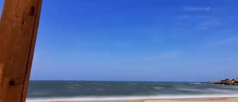 Vista a la playa con una estructura de madera y un cielo azul despejado.