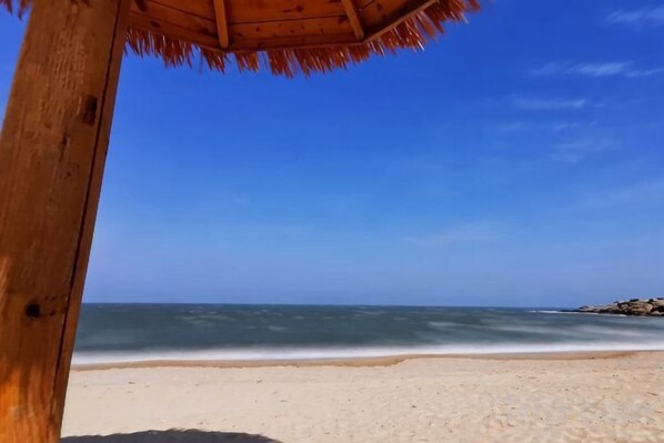 A beach view with a wooden structure and a clear blue sky.