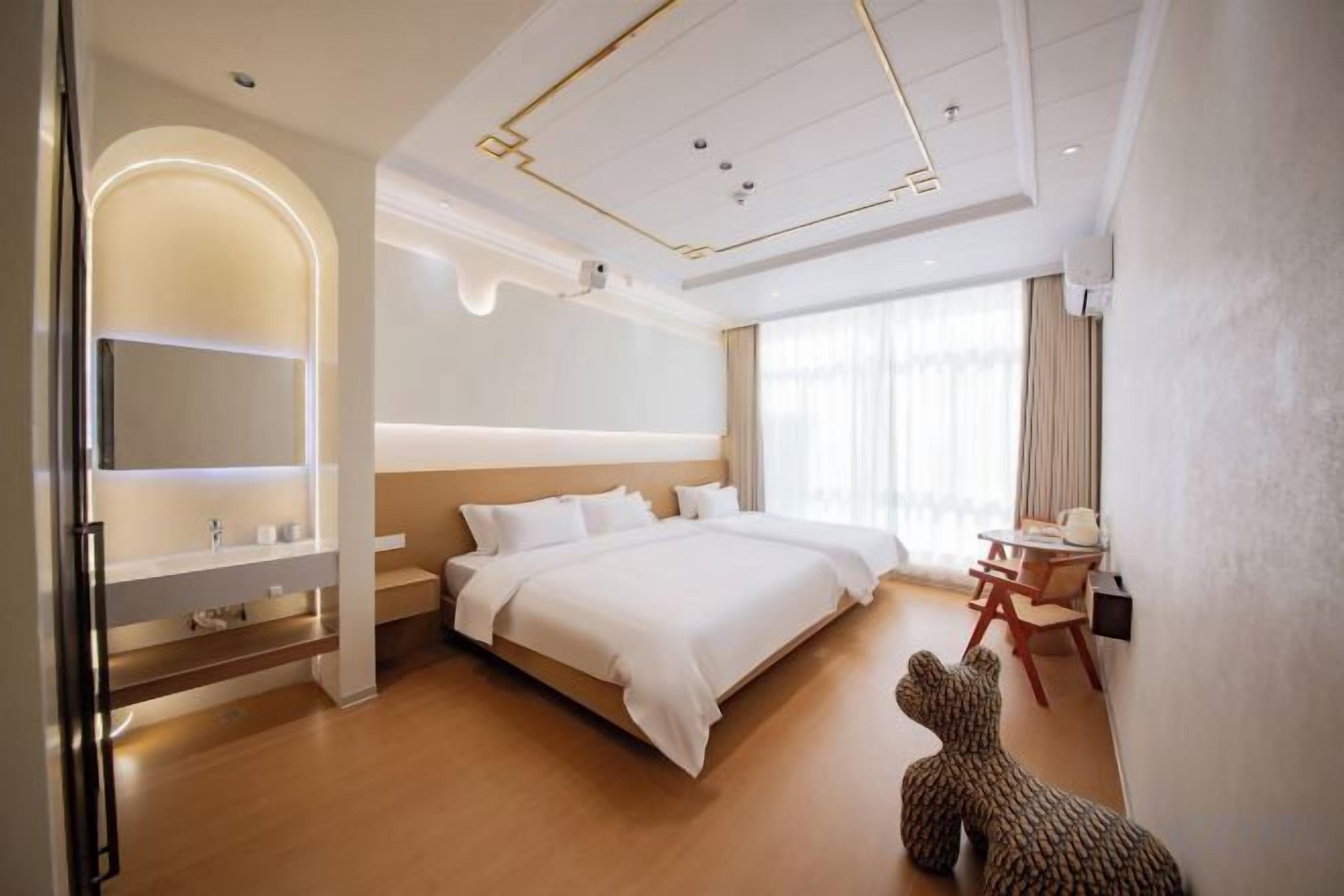 A hotel room with a large bed, a desk, and a chair.