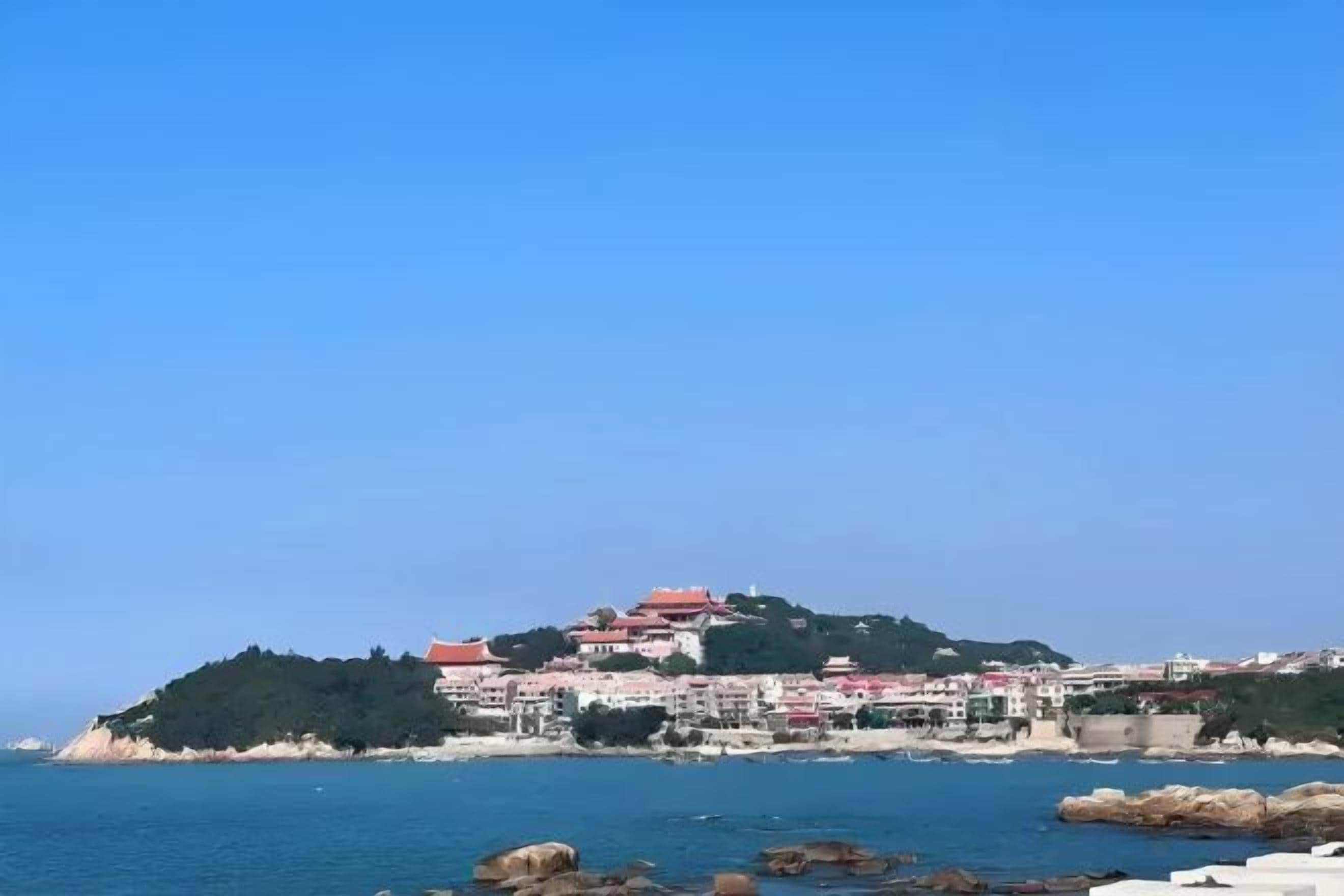 A coastal town with buildings on a hill overlooking the sea.