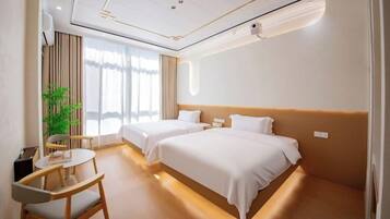 Una habitación de hotel con dos camas, un escritorio, una silla y un ventanal grande.