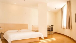 A hotel room with a bed, bedside table, lamp, desk, chair, and curtains. - Elan Hotel (Yantai Muping Bus Station) (Yantai)
