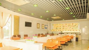 A modern restaurant with a long counter, orange chairs, and a menu board displaying various dishes. - Elan Hotel (Yantai Muping Bus Station) (Yantai)