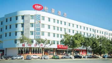 Un hotel con un llamativo letrero 'elan', varios pisos y un estacionamiento con coches.